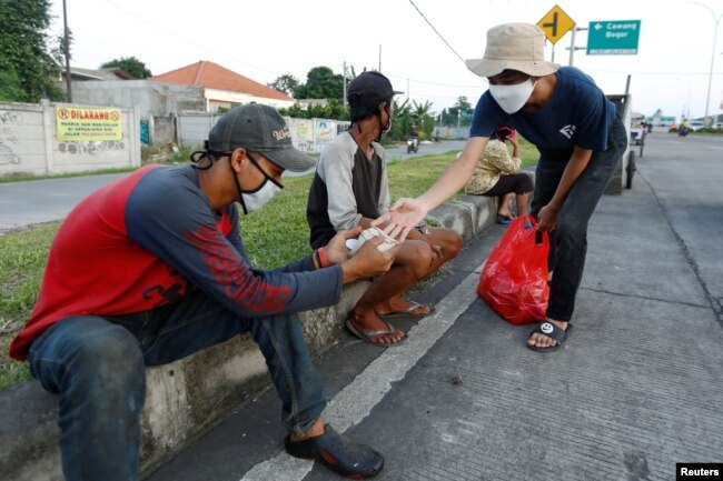 Seorang relawan membagikan makanan gratis di tengah pandemi virus corona (Covid-19) di Jakarta, 16 Mei 2020. (Foto: Reuters)