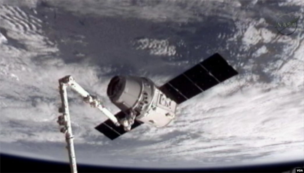 This image provided by NASA-TV shows the SpaceX Dragon commercial cargo craft, top, after Dragon was grappled by the Canadarm2 robotic arm and connected to the International Space Station, May 25, 2012. (NASA-TV).