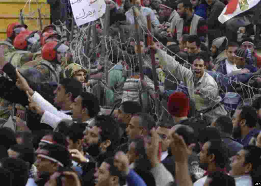 An anti-government protesters try to remove the fence in front the Egyptian television headquarters, in Cairo, Egypt, Friday, Feb. 11, 2011. Egypt exploded with joy, tears, and relief after pro-democracy protesters brought down President Hosni Mubarak wit