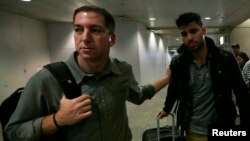 U.S. journalist Glenn Greenwald (L) walks with his partner David Miranda in Rio de Janeiro's International Airport, August 19, 2013. 