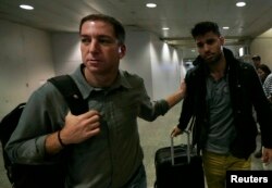 FILE - U.S. journalist Glenn Greenwald (L) walks with his partner David Miranda in Rio de Janeiro's International Airport, August 19, 2013.