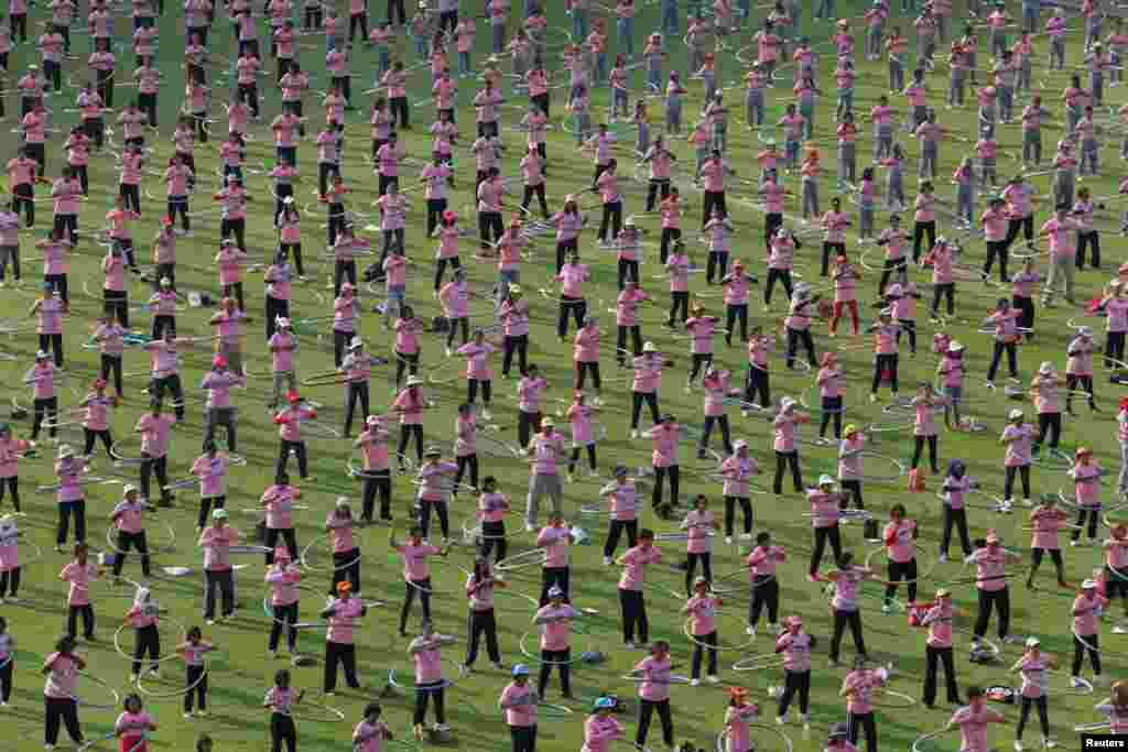 Miles de personas participan de un evento para romper el récord Guiness al reunir al mayor número de individuos realizando simultáneamente hula-hula en el estadio de la universidad Thammasat en la provincia Pathum Thani, en Tailandia.