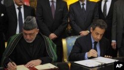 France's President Nicolas Sarkozy (R) and Afghanistan's President Hamid Karzai sign a friendship and cooperation treaty at the Elysee Palace in Paris, January 27, 2012.