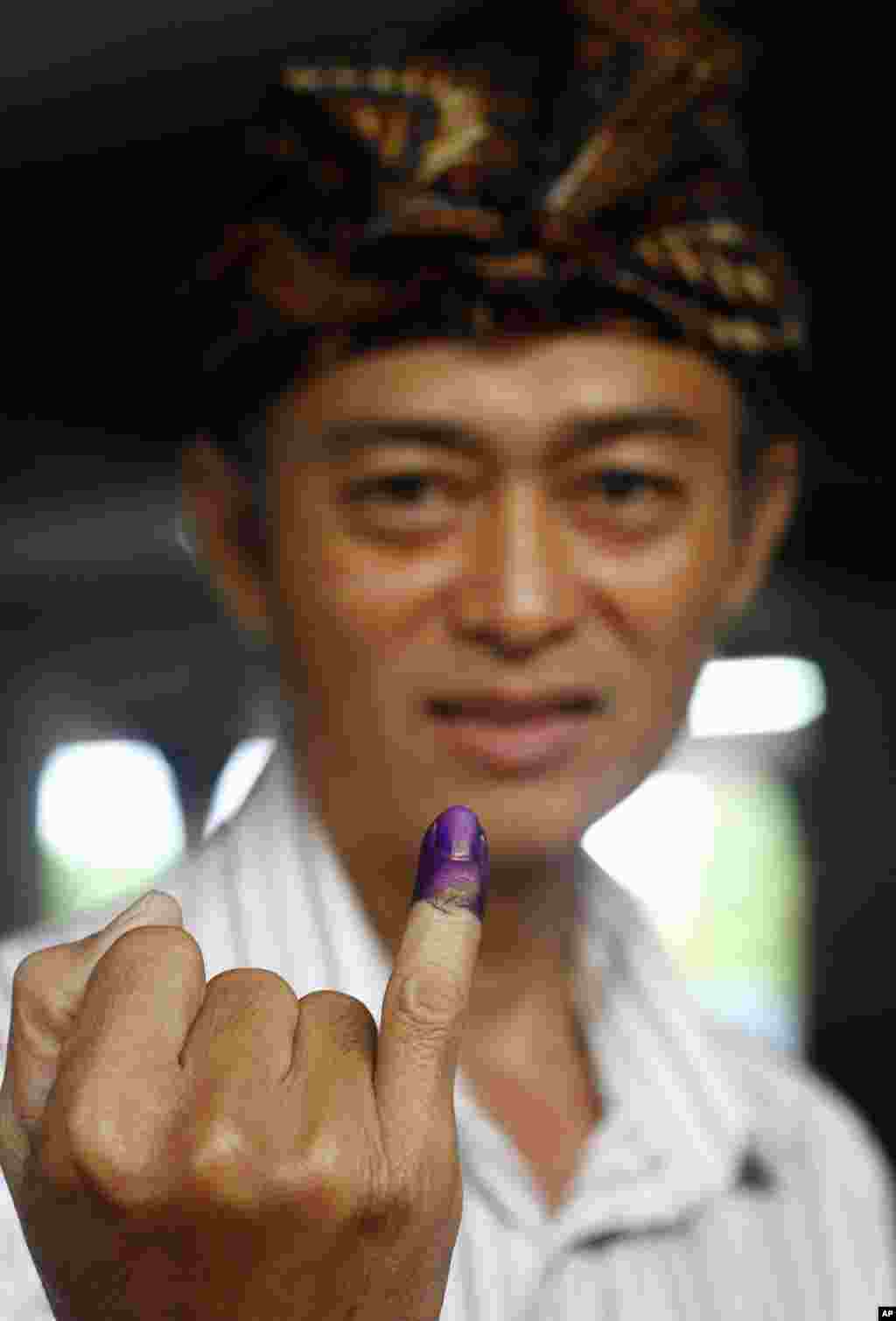 Seorang pemilih menunjukkan jarinya yang bertinta tanda telah memberikan suara dalam pemilihan presiden di Bali (9/7).&nbsp;(AP/Firdia Lisnawati)