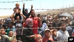 FILE - Syrian refugees gather at the Turkish border as they flee intense fighting in northern Syria between Kurdish fighters and Islamic State militants in Akcakale, southeastern Turkey, June 15, 2015.