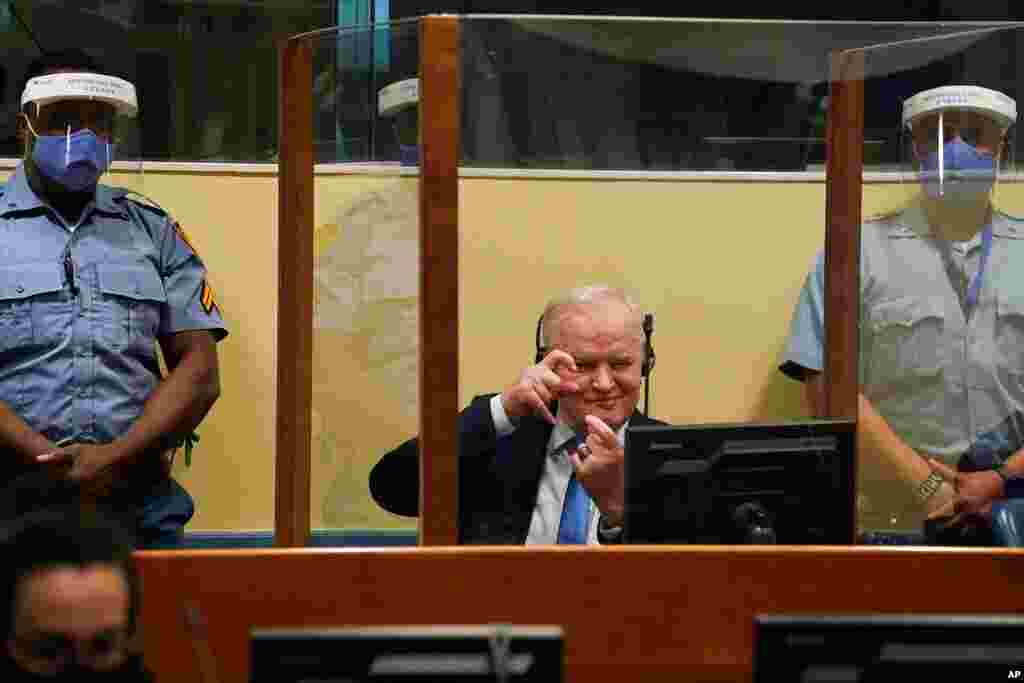 Former Bosnian Serb military chief Ratko Mladic imitates taking pictures as he sits the courtroom in The Hague, Netherlands, where the U.N. court delivers its verdict in the appeal of Mladic against his convictions for genocide in the Bosnian war. 