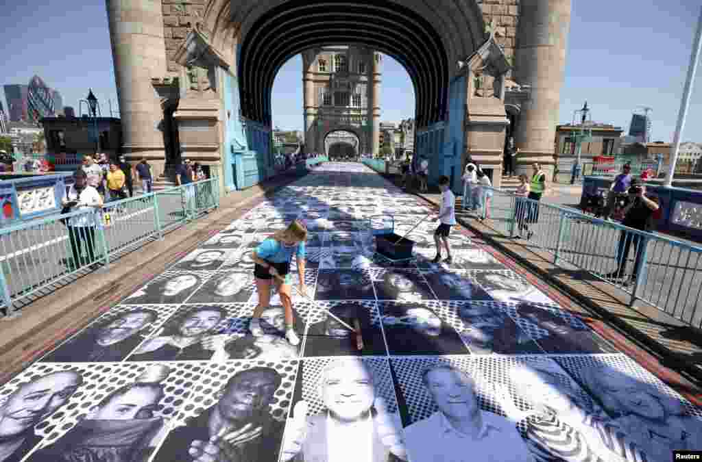 Workers place portraits of Londoners, including London&#39;s Mayor Sadiq Khan, by French artist JR, on the road at Tower Bridge to celebrate UEFA Euro 2020, in London.