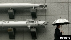 FILE - A man holding an umbrella walks past a torpedo on display outside the Taiwan Armed Forces Museum in Taipei, Jan. 7, 2010. The U.S. State Department has approved a potential arms sale to Taiwan.