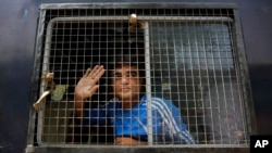 An unidentified Indian man accused on a 2002 riot case waves to supporters as he arrives at Ahmadabad's court, India, Thursday, June 2, 2016.