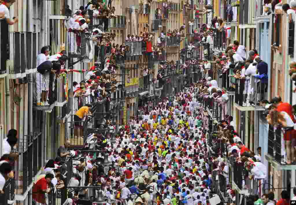 Runners make their way through the street with "El Pilar" fighting bulls watched by people from their balconies during the running of the bulls at the San Fermin festival, in Pamplona, Spain, July 12, 2013.