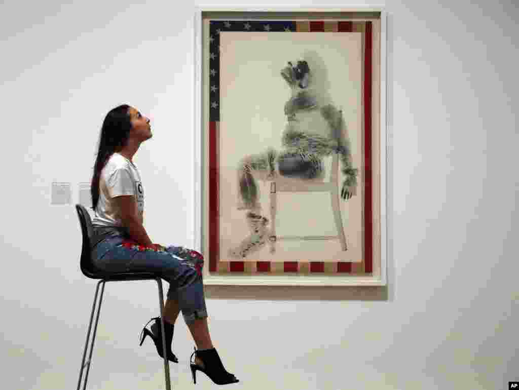 A woman poses as David Hammon&#39;s painting on an America flag &#39;Injustice case&#39; at the exhibition Soul Of A Nation, exploring the art made by African American artists between 1963 and 1983, in London, July 11, 2017.