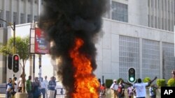 图为马拉维一名抗议者7月20日在街头焚烧树枝。