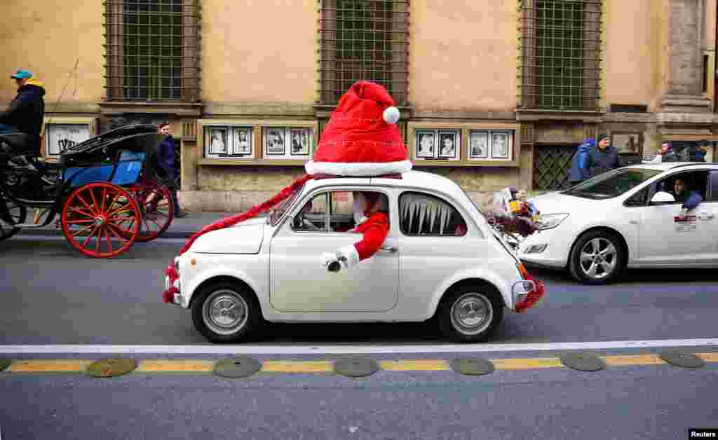 Seorang pria berpakaian Santa Claus membunyikan bel sambil mengendarai Fiat 500 di kota Roma, Italia.