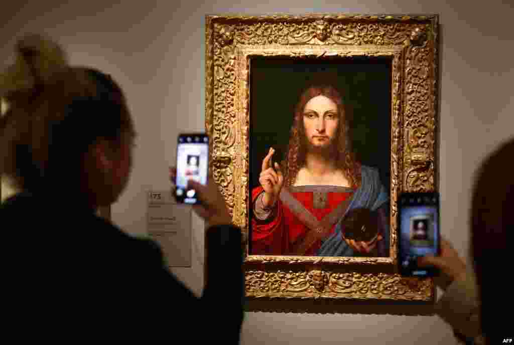 People take pictures of an oil painting by Leonardo da Vinci, &quot;Salvator Mundi,&quot; during the opening of the exhibition &quot;Leonardo da Vinci, &quot; at the Louvre museum in Paris, France.