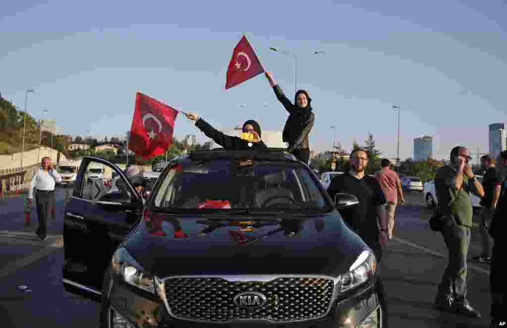 Turkish people wave the national flags on a car in Istanbul, Turkey, Saturday, July 16, 2016.