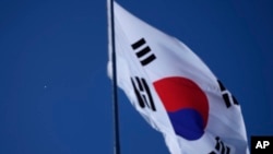 A South Korean national flag flutters in the wind at the Unification Observation Post as North Korean balloons, left, fly in Paju, South Korea, near the border with North Korea, Oct. 4, 2024.