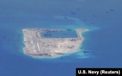 FILE - Chinese dredging vessels are purportedly seen around Fiery Cross Reef in the disputed Spratly Islands in the South China Sea in this image from video taken by a P-8A Poseidon surveillance aircraft provided by the U.S. Navy.
