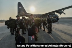 Indonesian soldiers gather by a Hercules military plane heading to Palu at Halim Perdanakusuma military base in Jakarta, Indonesia, Sept. 29, 2018.