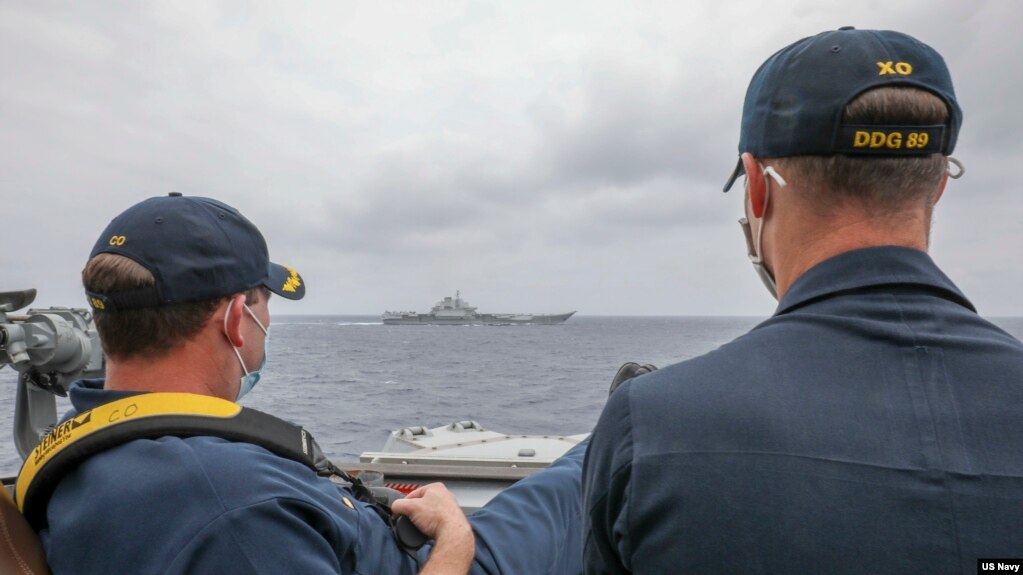 资料照片：美国海军公布的照片显示，两位美国海军中校罗伯特·J·布里格斯与理查德·D·斯莱2021年4月4日在阿利·伯克级导弹驱逐舰“马斯廷号”驾驶舱进行水面接触观察。照片中可见中国'辽宁号'航空母舰及其舷号。(photo:VOA)