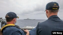 资料照片：美国海军公布的照片显示，两位美国海军中校罗伯特·J·布里格斯与理查德·D·斯莱2021年4月4日在阿利·伯克级导弹驱逐舰“马斯廷号”驾驶舱进行水面接触观察。照片中可见中国"辽宁号"航空母舰及其舷号。