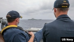 資料照片：美國海軍公佈的照片顯示，兩位美國海軍中校羅伯特·J·布里格斯與理查德·D·斯萊2021年4月4日在阿利·伯克級導彈驅逐艦“馬斯廷號”駕駛艙進行水面接觸觀察。照片中可見中國"遼寧號"航空母艦及其舷號。
