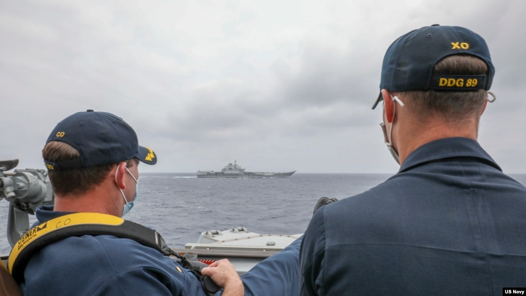 资料照片：美国海军公布的照片显示，两位美国海军中校罗伯特·J·布里格斯与理查德·D·斯莱2021年4月4日在阿利·伯克级导弹驱逐舰“马斯廷号”驾驶舱进行水面接触观察。照片中可见中国'辽宁号'航空母舰及其舷号。(photo:VOA)