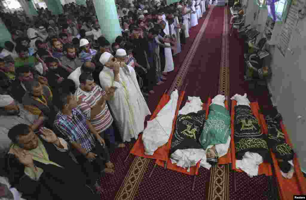 People pray next to the bodies of Palestinians, including three members of the Sheik al-Eid family who medics said were killed in an Israeli airstrike, during their funeral at a mosque in Rafah in the southern Gaza Strip, July 15, 2014.