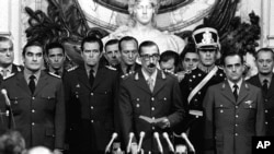 Argentine Dirty War: FILE - In this March 24, 1976 file photo, Gen. Jorge Rafael Videla, center, is sworn-in as president at the Buenos Aires Government House accompanied by Adm. Emilio Massera, second from left, and Brig. Orlando Agosti, second from right, members of the junta that overthrew President Isabel Peron. The former Argentine dictator died of natural causes Friday, May 17, 2013, while serving life sentences at the Marcos Paz prison for crimes against humanity. Videla took power in a 1976 coup and led a military junta that killed thousands of his fellow citizens in a dirty war to eliminate "subversives." He was 87. 