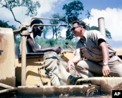 FILE - A Peace Corps volunteer works with a caterpillar driver on the Great Ruaha road project in Tanganyika, present-day Tanzania, in 1962. They were working to secure better access to a sugar refinery.