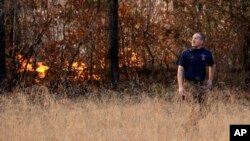 Assistant Chief Brent Masey, of the Highway 58 Fire Department in Harrison, Tenn., looks up as a helicopter carrying fire retardant flies over as Masey keeps watch on a wildfire, in Soddy-Daisy, Tenn. Nov. 10, 2016.