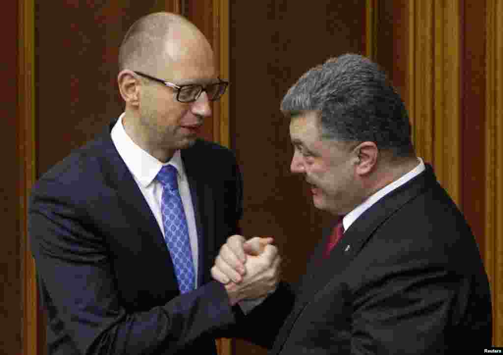 Ukraine&#39;s President Petro Poroshenko (right) clasps hands with Prime Minister Arseniy Yatsenyuk after the ratification of a landmark association agreement with the European Union during a parliamentary session in Kyiv, Sept. 16, 2014.