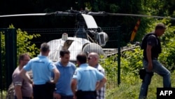 This picture taken July 1, 2018, in Gonesse, north of Paris, shows police near a helicopter abandoned by notorious French gangster Redoine Faid after his escape from prison in Reau, France.