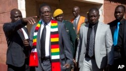 Presiden Zimbabwe Emmerson Mnangagwa (kedua dari kiri) meninggalkan TPS setelah memberikan suara dalam Pilpres di kota Kwekwe, Senin (30/7). 