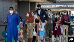 FILE - Families evacuated from Kabul, Afghanistan, walk through the terminal to board a bus after they arrived at Washington Dulles International Airport, Aug. 31, 2021, in Chantilly, Va.