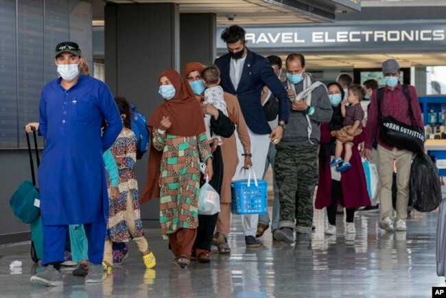 Keluarga Afghanistan yang dievakuasi dari Kabul, berjalan melalui terminal untuk naik bus setelah mereka tiba di Bandara Internasional Washington Dulles, 31 Agustus 2021. (Foto: AP)