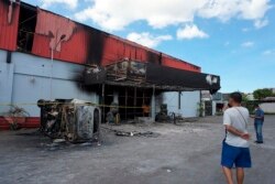 Seorang pria mengamati klub malam di kota Sorong, provinsi Papua Barat, yang hangus terbakar setelah dua geng bentrok di tempat tersebut, Selasa, 25 Januari 2022.(Foto AP)