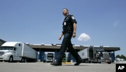 FILE - U.S. Customs and Border Protection officer Kevin Corsaro walks past a truck inspection station at the U.S. border in Buffalo, N.Y.