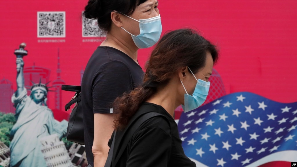 北京街头行人走过有着美国国旗和纽约自由女神画像的广告牌。（2020年8月6日）(photo:VOA)