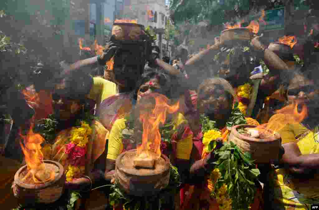 Indian members of the All India Anna Dravida Mennetra Kazhgam organization carry burning pots during a ritual offered for the health of Tamil Nadu Chief Minister Jayalalithaa Jayaram near the hospital where she is being treated in Chennai.