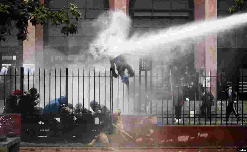 A student is hit by a jet of water sprayed by riot police during a protest against the government to demand changes in the public state education system, in Santiago, Chile.