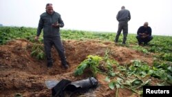 Israeli security forces stand next to the remains of a rocket that was fired from the Gaza Strip toward Israel on Friday, on the Israeli side of the border, Dec. 19, 2014. 