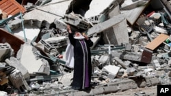 A Palestinian woman reacts near the rubble of a building housing The Associated Press, broadcaster Al-Jazeera and other media outlet, in Gaza City. The building was destroyed by an Israeli airstrike on Saturday.