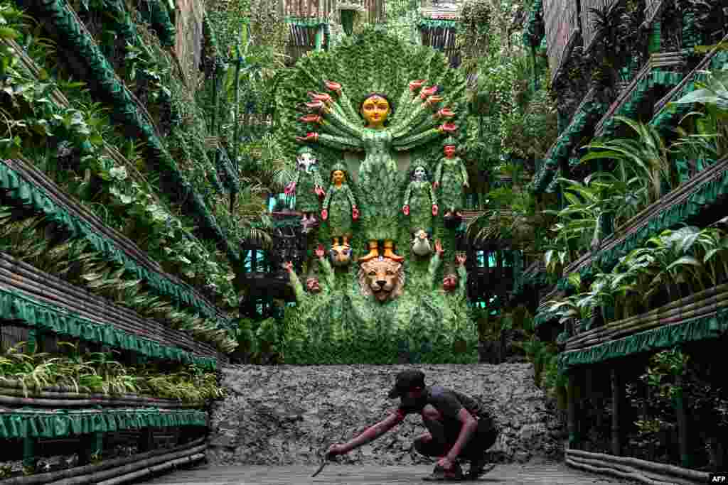 An artisan gives a finishing touch to a Durga Puja 'Pandal' (temporary place for worship) next to an idol of the Hindu Goddess Durga, as a part of the 'Durga Puja' festival in Kolkata, India, Oct. 5, 2024.