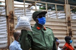 FILE - A member of the country's armed forces, the Uganda People's Defence Force, helps distribute food to people affected by the lockdown measures aimed at curbing the spread of the new coronavirus, in Kampala, Uganda, April 4, 2020.