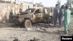 FILE - Residents look at an Army vehicle that was damaged during battle between Afghan security forces and Taliban in Farah province, Afghanistan, May 16, 2018. The Taliban have since agreed to a unilateral cease-fire from the Afghan government. 