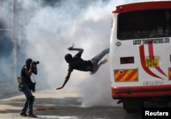A supporter of Kenyan opposition leader Raila Odinga of the National Super Alliance (NASA) coalition jumps from a bus after riot police fired tear gas canisters to disperse them after his swearing-in ceremony in Nairobi, Jan. 30, 2018.