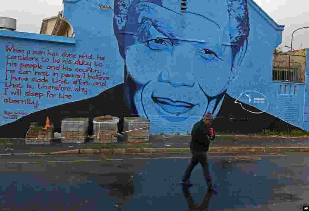 A woman walks past a mural with the face of former South African President Nelson Mandela in Cape Town, South Africa, July 18, 2014.