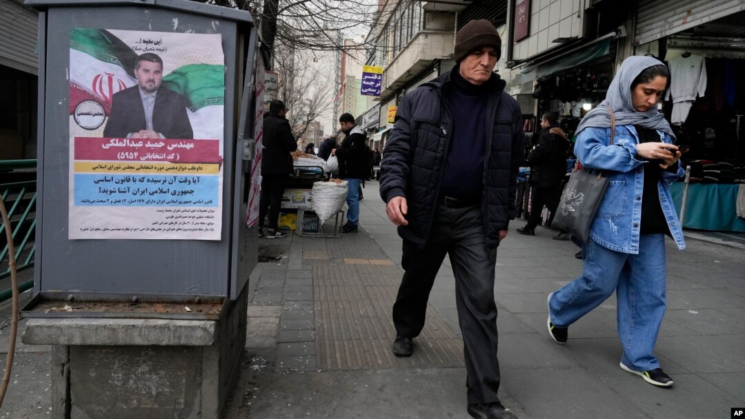 People walk past a campaign poster for Hamid Abdolmaleki, a candidate for the March 1 parliamentary election, in Tehran, Iran, on Feb. 22, 2024. This will be Iran's first election since the 2022 nationwide protests that followed the death of Mahsa Amini in police custody.