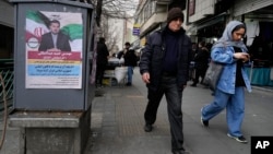 People walk past a campaign poster for Hamid Abdolmaleki, a candidate for the March 1 parliamentary election, in Tehran, Iran, on Feb. 22, 2024. This will be Iran's first election since the 2022 nationwide protests that followed the death of Mahsa Amini in police custody.