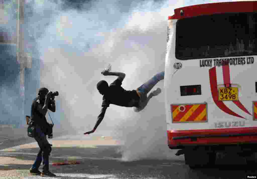 A supporter of Kenyan opposition leader Raila Odinga of the National Super Alliance (NASA) coalition jumps from a bus after riot police fired teargas canisters to disperse protesters after his swearing-in ceremony in Nairobi.